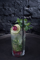 close-up, advertising shot of a light alcoholic cocktail, with a sprig of mint, icing sugar, with decorative grape berry. In a rustic style, on a dark background.