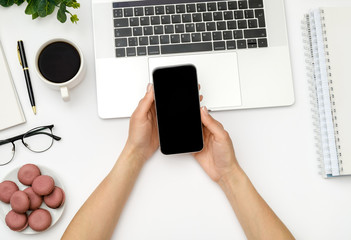 Woman is using smartphone with blank screen over white office desk