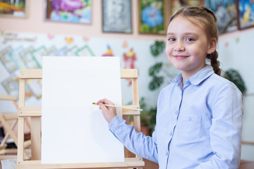 Girl at easel with paper and paint brushes