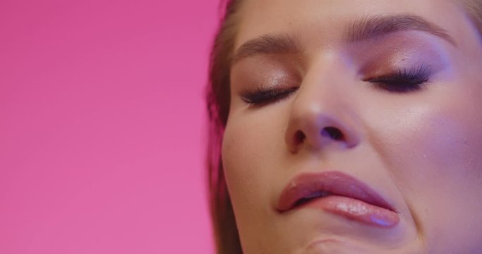 Seductive woman looking in camera on pink background. Portrait of sexy girl in studio. Brunette woman with sexy lips. Fashion model face. Glamour lady touching face and biting her lips.