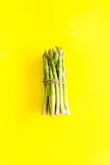 Bunch of asparagus steams on yellow background top-down copy space