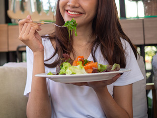 Asian woman enjoys eating a salad in her hand. Choosing food that is good for the body. The concept of good weight loss.