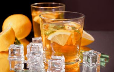 Two glasses of cold refreshment tea with ice and lemon fruit.