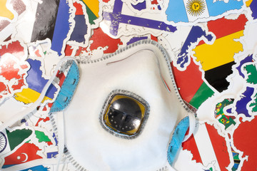 Worldwide healthcare problem concept. Medical respirator top view on country flags. Protective face mask as a sign of protection from infection or disease