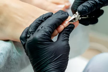 Rolgordijnen Pedicure master cuts foot nails of woman during pedicure procedure. © okskukuruza