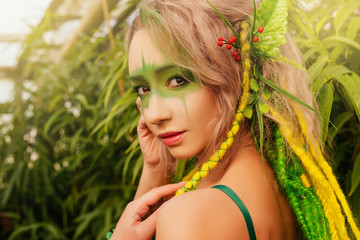 Dryad stands among the trees. Portrait of a beautiful girl with makeup on her face. Forest Nymph