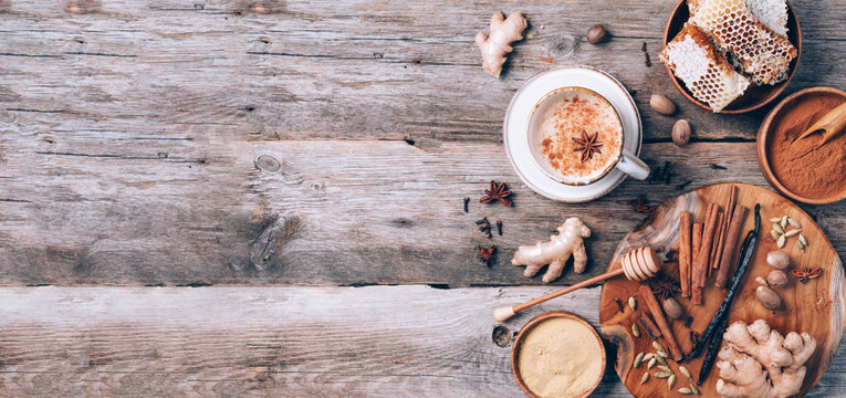 Tea with milk, cloves, ginger, cardamom, cinnamon, anise, vanile, honey, nutmeg. Indian masala tea with spices. Top view, copy space. Antiviral beverage. Healthy ayurvedic spice drink chai