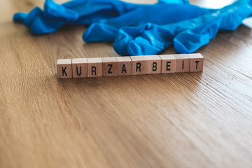 Kurzarbeit-Konzept aus Holzwürfeln mit Schutzhandschuhen