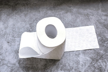 Roll of white soft toilet paper on dark background. Personal hygiene concept. Flat lay, top view.
