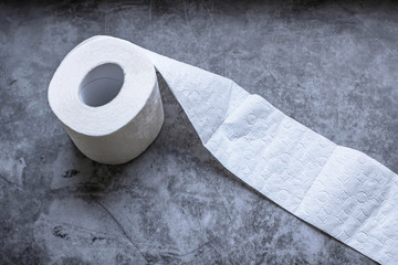 Roll of white soft toilet paper on dark background. Personal hygiene concept. Flat lay, top view.