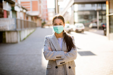 Fototapeta premium Pretty young woman with protective facial mask on the street