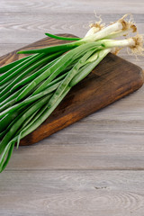 Healthy and wholesome food. Fresh and fragrant green onions on a wooden table