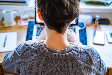 Home office work. Young caucasian short hair woman working online from home on computer laptop from back, head and shoulders