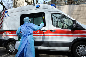 Paramedics disinfecting the ambulance car with the motorized backpack sprayer