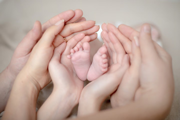 Obraz na płótnie Canvas Hands of the family hold the legs of a newborn