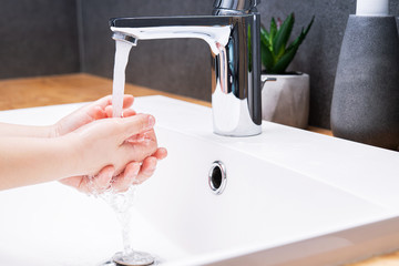 Child washing hands with soap in the bathroom