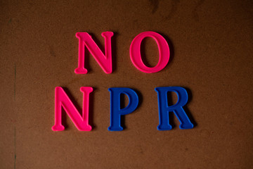 'NO NPR' written on a brown wooden background.