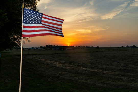 An amarican flag on the fence of a farm near the city of Commerce in the State of Oklahoma, at sunset, USA.