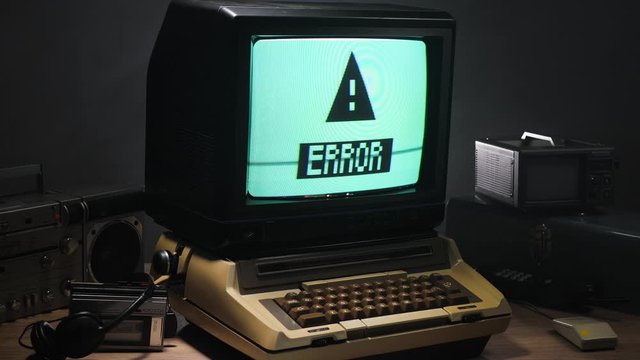 Vintage computer setup from the 70s 80s with error message blinking on the monitor. Old tech concept.