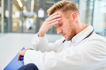 Junger Mann als Arzt mit der Hand an der Stirn