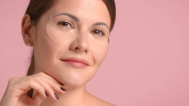 Brunette woman closeup portrait wears an eye patches treatment. self-care home facial treatment