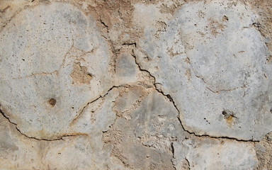 Cracked pieces and falling off gray-white stucco with cracks.