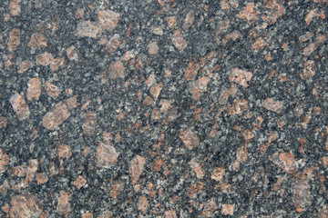 The structure of black granite with transparent pink large splashes. Stone background from granite. Smooth cut.