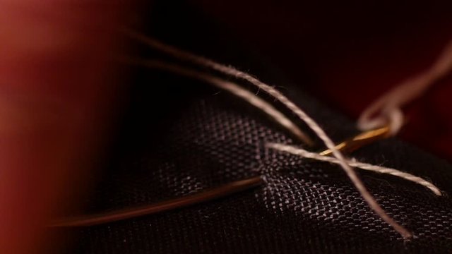 Macroscopic shot of man tailor hand sewing black line with white basting thread. Basting is sewing long, easily removable running stitches, by machine or by hand. It is also called tacking. 