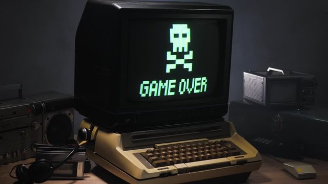 Vintage computer setup from the 70s 80s with game over message blinking on the monitor. Old technology concept...
