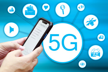 The hand of a person holding a mobile phone with a 5G symbol and information , soft blur background
