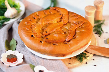 Round closed homemade baked pie with potatoe and fish