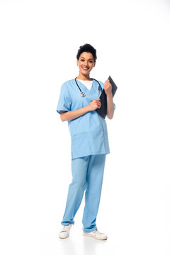 Full length view of african american nurse with stethoscope holding clipboard and smiling on white background