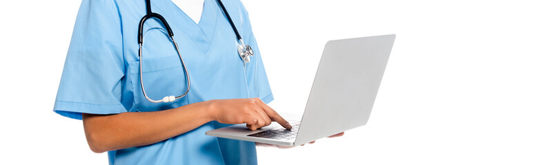 Cropped view of african american nurse with stethoscope focused on using laptop isolated on white, panoramic shot