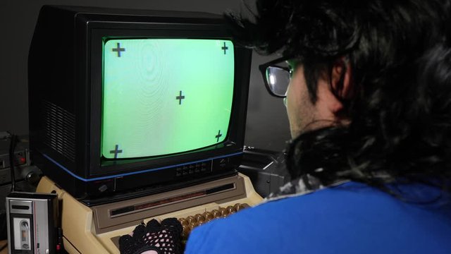 Vintage style nerd looking at a green chroma key screen on an old concept computer from 70s 80s
