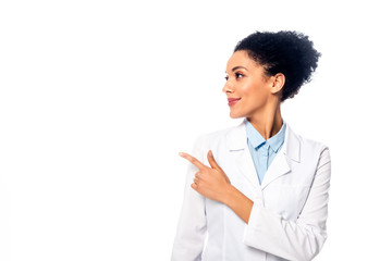 Front view of african american doctor smiling and pointing aside isolated on white