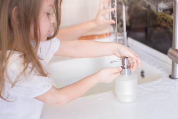 Obraz na płótnie Canvas Little girls wash their hands in the sink with soap in the foam. Protection against coronovirus covid-2019 using personal hygiene and antibacterial gel.Mom takes care of health of children and family