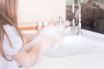 Little girls wash their hands in the sink with soap in the foam. Protection against coronovirus covid-2019 using personal hygiene and antibacterial gel.Mom takes care of health of children and family