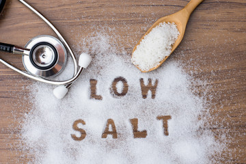 White granulated natural sea salt in wooden scoop and words
