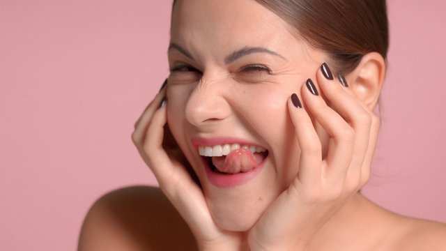 Brunette woman closeup portrait making faces and having fun after facial treatment