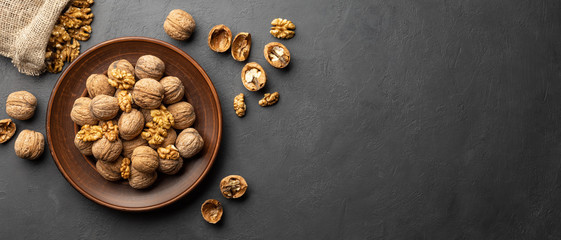 Nuts. Walnut kernels and whole walnuts on dark stone table. Black background. Top view, flat lay...