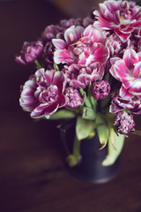 Bouquet of pink wilted tulips in a vase on a dark background