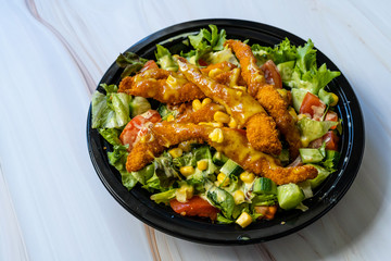 Take Away Healthy Cajun Salad with Chicken Fingers and Mustard Sauce in Black Plastic Plate Box / Package.