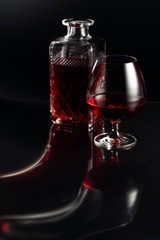 Glass of brandy and a carafe on a dark background.