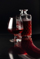 Glass of brandy and a carafe on a dark background.