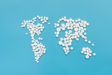 Covid-19.  World map shape make from white pills on blue background. Flu, illness concept