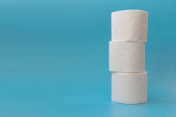 Stack of toilet paper rolls on blue background. Copy space