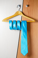A man's blue tie hangs on the door of the chiffonier. The concept of a successful man's style.