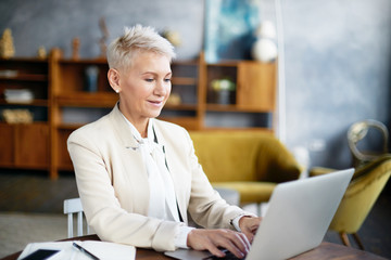 Technology, occupation, electronic gadgets and aging concept. Serious middle aged female with...