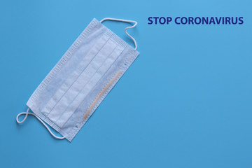 Medical disposable mask on a blue background. The inscription Stop Coronavirus