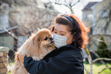 Mature Woman in mask with his pet on street because of air pollution and epidemic in city. Protection against virus, infection.